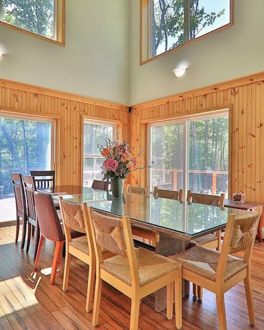 Dining area of a rental house in Killington, Vermont, with large windows leading to a yard.