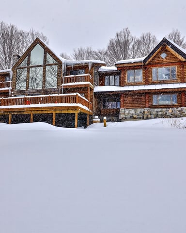 Entryway of a large home surrounded by trees and lawn.