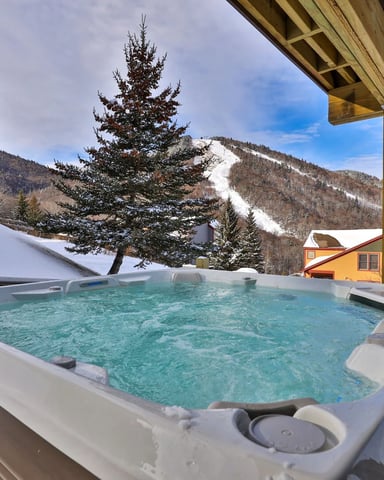 Hot tub steaming on a snowy deck in the Vermont woods.