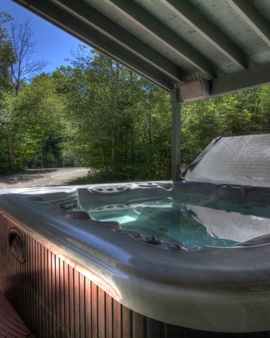 Person in outdoor hot tub with snowy mountain valley view